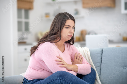 Full-figured young woman in a pink shirt feeling depressed