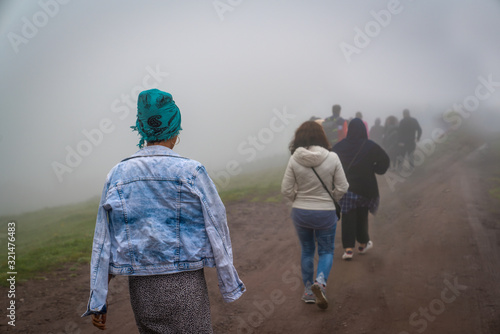 Back view of refugees walk to the border in a cold day under fog