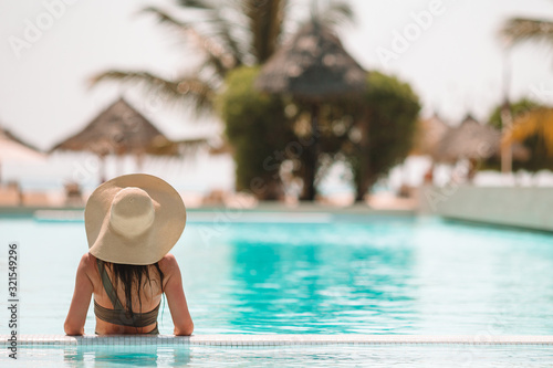 Woman relaxing by the pool in a luxury hotel resort enjoying perfect beach holiday vacation