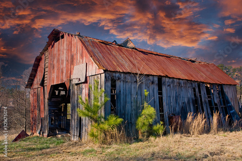 An old barn with a rusty roof in a rural area