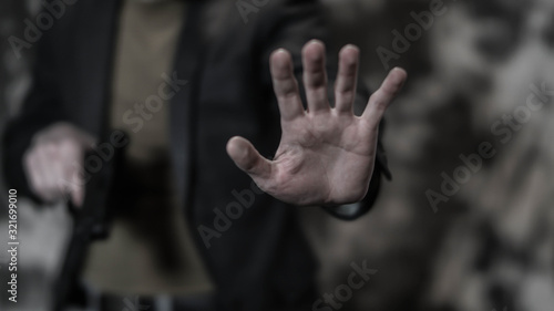 Man holding out hand while drawing a concealed pistol. Personal protection concept