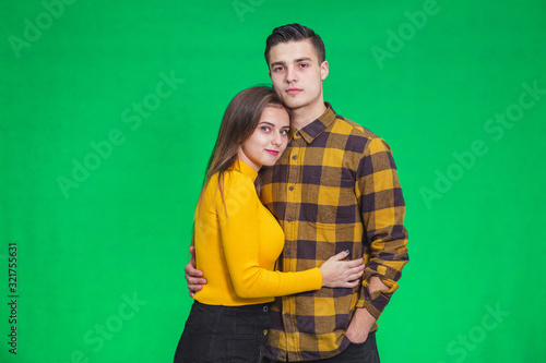 Stylish couple in autumn outfits posing isolated on green background.