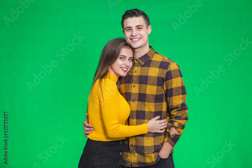 Stylish couple in autumn outfits posing isolated on green background.