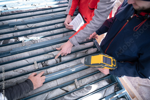 team of mining workers measuring drilled rock core