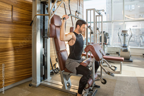 Handsome man exercising on lat pull down machine