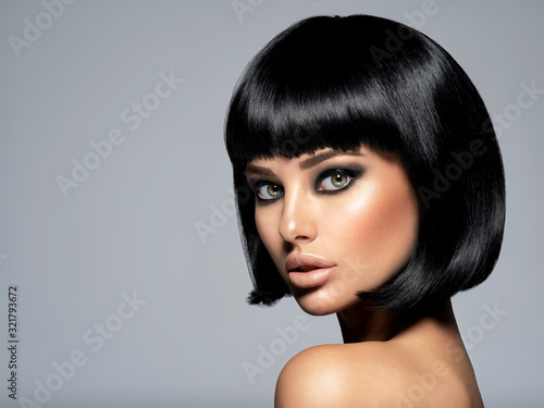 Beautiful fashion woman with a bob hairstyle looks to the camera. Сloseup face of a sexy fashion model with black gloss make-up, Attractive white girl with black eye-makeup. Art.
