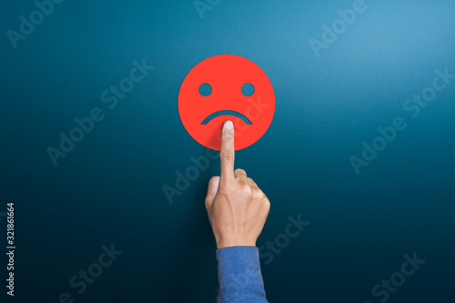 The client's hand choose the red sad face icon, Customer service evaluation, dissatisfaction in service concepts, copy space