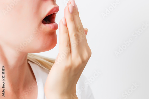 Health Care: Woman checking her breath with hand. Closeup portrait headshot sleepy young woman with wide open mouth Unrecognizable