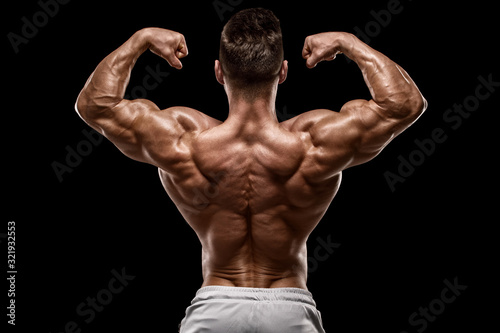 Muscular man showing back muscles rear view, isolated on black background. Strong male naked torso