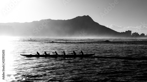 Outrigger canoe crews at sunrise at Waikiki in monochrome as silhouettes