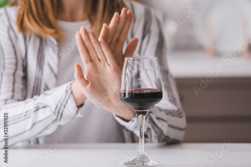 Woman refusing to drink wine at home. Concept of alcoholism