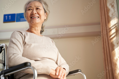 happy old woman sitting in wheelchair in nursing home
