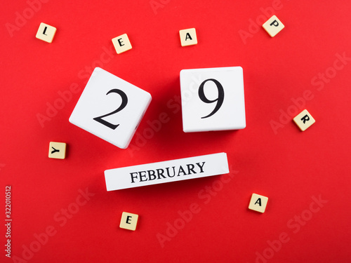 Leap year flat lay concept with wooden calendar on red background