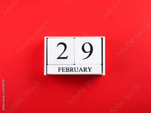 Leap year flat lay concept with wooden calendar on red background