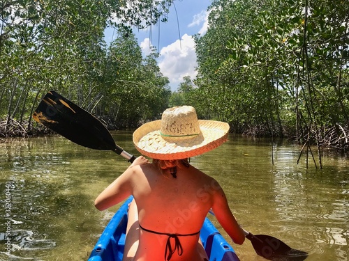 Woman with straw hat and sunglass in kayak, with paddle, in mangrove forest, cebu island, Philippines