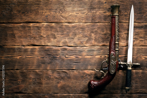 Ancient weapon on brown wooden table background with copy space. Pirate concept.