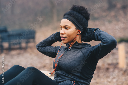 A young athletic woman doing situps in a park.