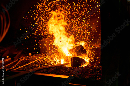 blacksmith furnace with burning fire and forging tools lying nearby