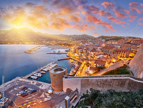 Amazing sunrise view from the walls of the citadel of Calvi, the old town with historic buildings. Luxurious marina and very popular tourist destination. Corsica, France, Europe.