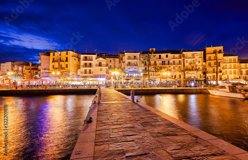 View from the waterfront of Calvi on the old town with historic buildings at night. Bay with yachts and boats. Luxurious marina and very popular tourist destination. Corsica, France, Europe.