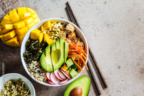 Vegan poke bowl with avocado, tofu, rice, seaweed, carrots and mango, top view. Vegan food concept.