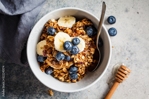 Homemade granola bowl with blueberries, banana and honey, top view.