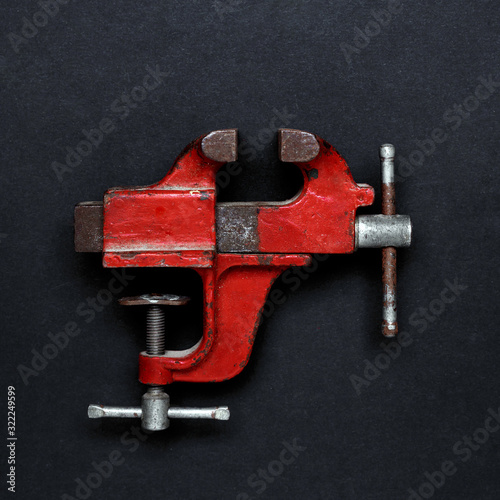 Vintage mechanical hand vise clamp red color on on grey background, top view. Creative design idea