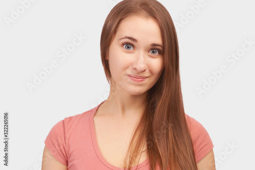 Beautiful euphoric teenage girl enjoying weekend at home, looking and smiling at camera. Beautiful young woman with long hair, clean smooth skin wears pink t-shirt isolated