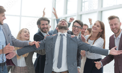 jubilant young businessman accepting the congratulations of his business team.