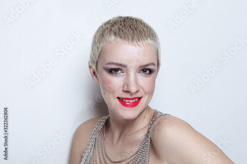 Vintage style portrait of young smiling woman with short blonde hair and fancy makeup