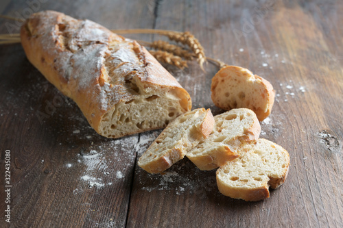 Half sliced baguette or French bread baked with onions on dark rustic wood