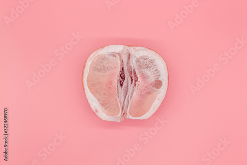 Sliced pomelo on a pink background, the concept of a female vagina