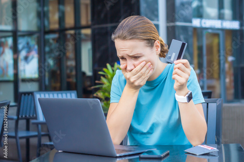 Nervous horrified confused young woman, stressed worried lady having problem with paying, buying online, payments with credit blocked bank card, looking at screen, monitor of laptop. Internet fraud