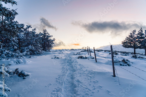 Snowy mountain road near a fence