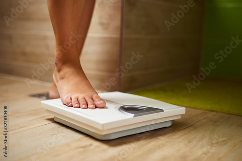 Woman weighing herself on weight scale in bathroom