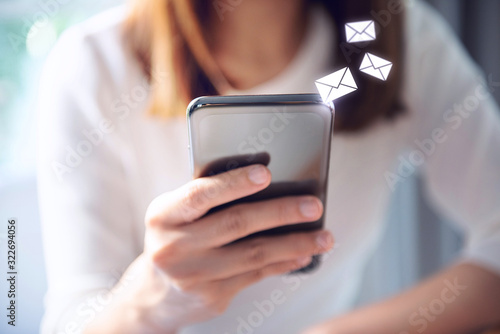 Email concept, Closeup Woman hand using mobile smartphone with email icon.