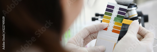 Female chemist holding litmus paper in hands. Analyzes ph test in a chemical laboratory. Chemistry industry education concept