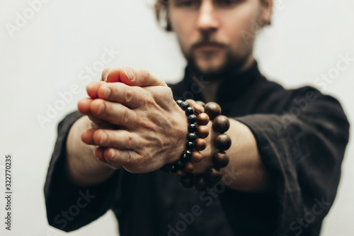 Close-up of palm together. The beads on the wrist. The rosary on hand. Hands pointing forward to the camera.