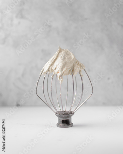 Cream colored american buttercream on a whisk attachment