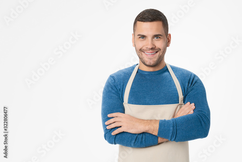 Young handsome shopkeeper man wearing apron standing over isolated white background