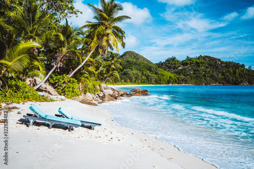 Mahe, Seychelles. Beautiful Anse intendance, tropical beach with relaxing lounger. Blue ocean, sandy beach and coconut palm trees. Travel concept