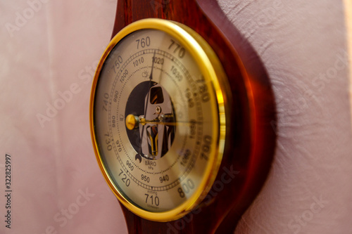 A vintage barometer Clock hangs on a pink wall.