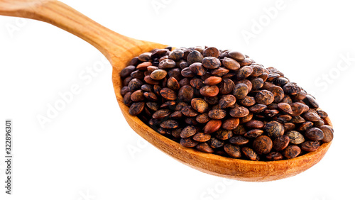 Brown lentils in the wooden spoon isolated on a white background. Top view.