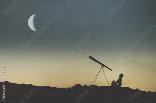 silhouette of a boy observing the sky on a starry night with his telescope