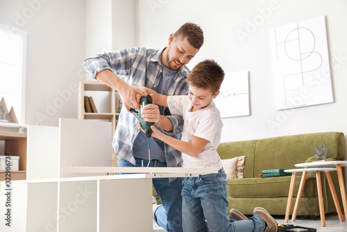 Father and his little son assembling furniture at home