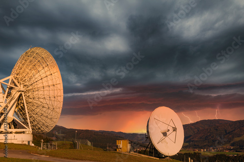 Parabolantennen einer Erdfunkstelle mit Blitz und Gewitter