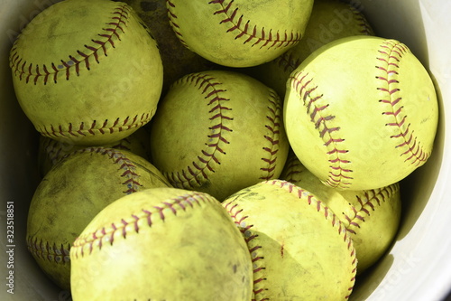 close up of bright yellowused softball with red stiching