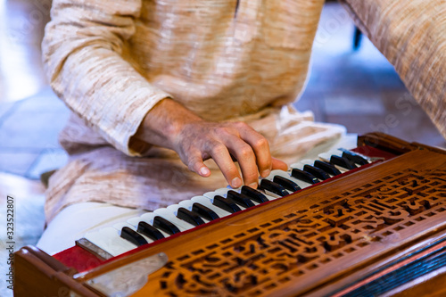 Closeup of shamanic male hands on harmonium keys playing sacred kirtan music for divine power and spiritual energy to connect with positive soul 