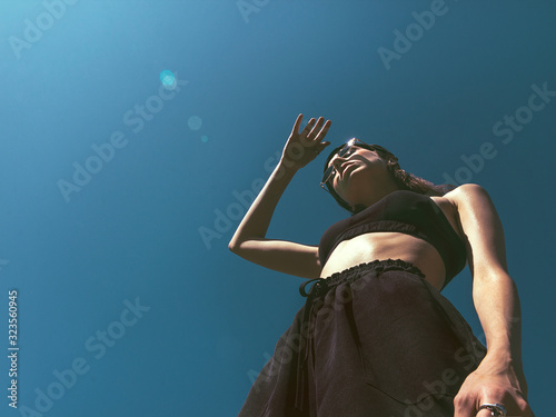 Girl on a tennis court The girl in black sportswear with sunglasses is looking at the sun Photo with copy space in bottom view