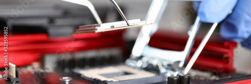 Close-up of workers hands repair computer. Man putting cpu on motherboard. Macro shot of intel microprocessor in the socket. Upgrade and technology concept